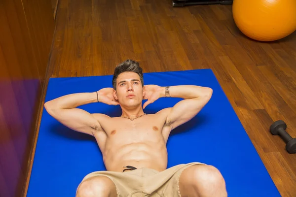 Handsome young man doing abs exercises on mat — Stock Photo, Image