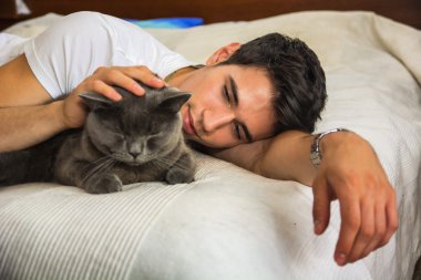 Yakışıklı genç adam Gri Kedi Evcil hayvanını kucaklıyor