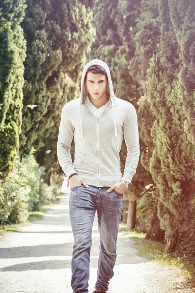 Handsome young man walking along rural road — Stock Photo, Image