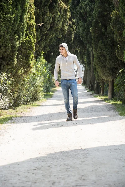 Bello giovane uomo che cammina lungo la strada rurale — Foto Stock