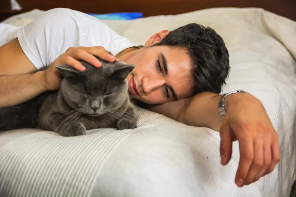 Yakışıklı genç adam Gri Kedi Evcil hayvanını kucaklıyor