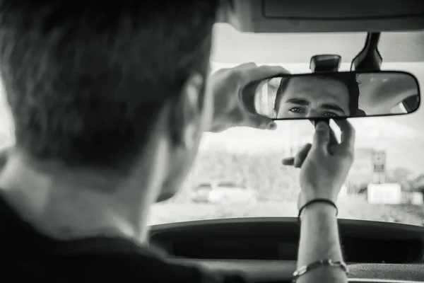 Young man in his car adjusting rear view mirror — Stock Photo, Image