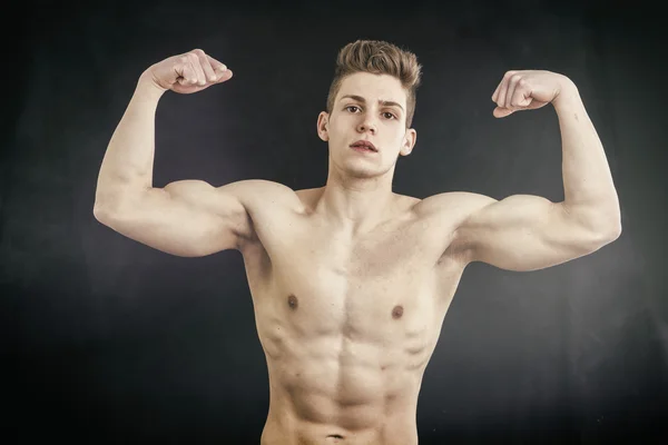 Shirtless muscular young man doing double biceps — Stock Photo, Image