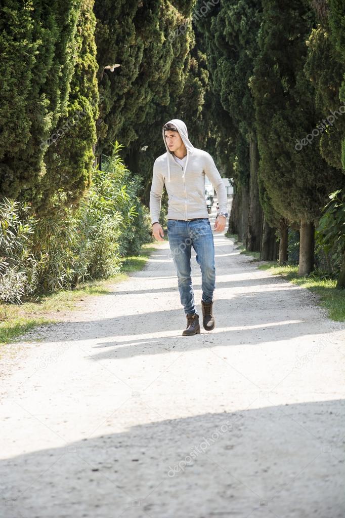 Handsome young man walking along rural road 