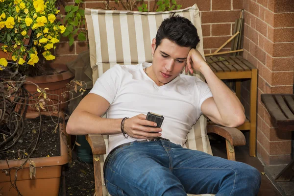 Pohledný mladý muž v balkon pomocí mobilního telefonu — Stock fotografie