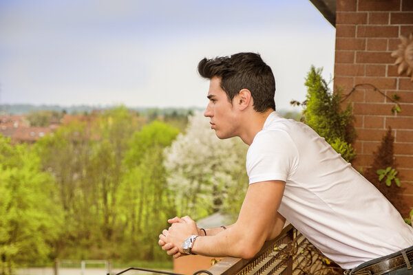 красивый темные волосатая молодой человек, глядя на балконе