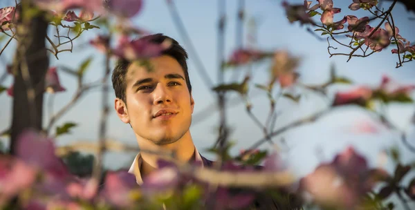 Bueno buscando modelo masculino en couuntryside, entre las flores — Foto de Stock