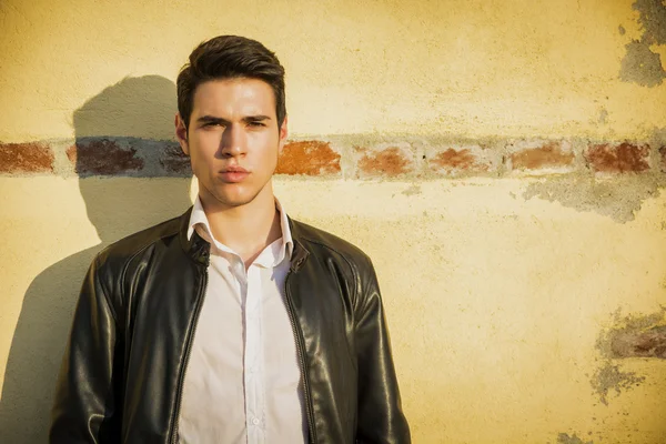 Handsome young man leaning against old wall — Stock Photo, Image