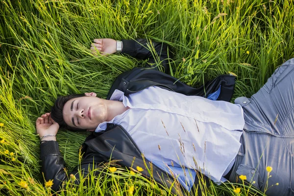 Good looking, fit male model relaxing lying on the grass