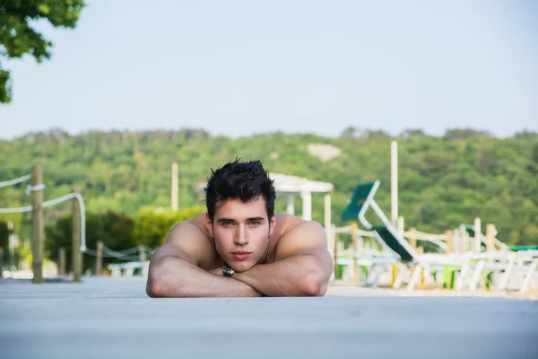 Jonge man liggend op de buik op zonnedek — Stockfoto