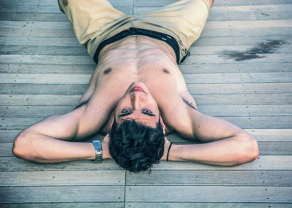 Junger Mann auf Rücken auf Sonnendeck liegend — Stockfoto