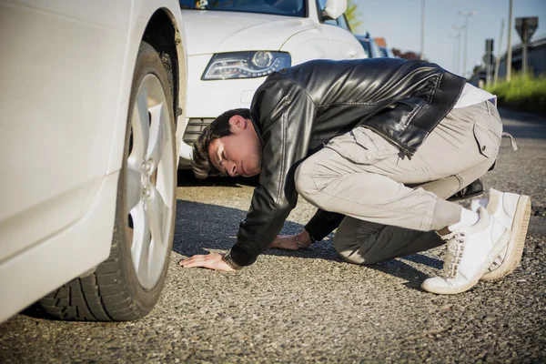 若い男が車の下を調べる — ストック写真