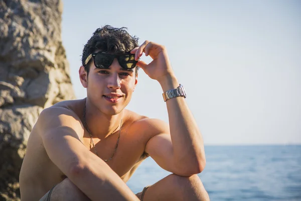 Handsome young man on beach with wet hair and sunglasses — Stok fotoğraf