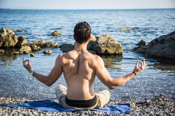 Junger Mann meditiert oder macht Yoga-Übungen auf dem Meer — Stockfoto