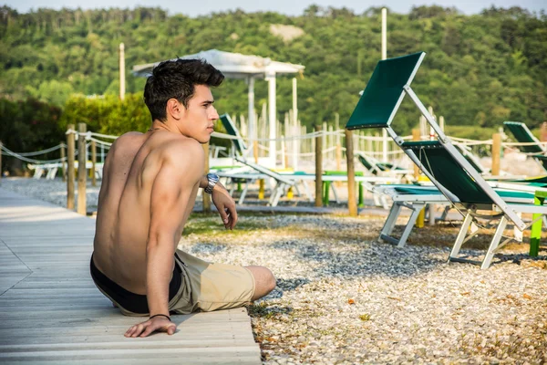 Young shirtless athletic man sitting at the beach — Foto de Stock