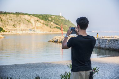 Rear View of Young Man Taking Photos at the Beach