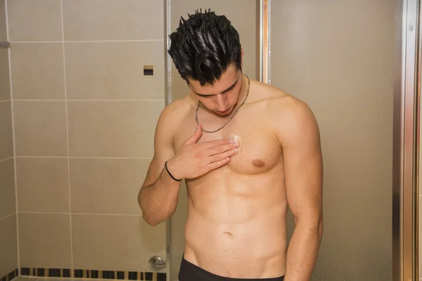 Muscular fit young man applying ointment to his chest — Stok fotoğraf