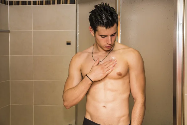 Muscular fit young man applying ointment to his chest — Stock Photo, Image