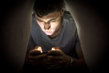 Teenage boy hiding while using a mobile phone