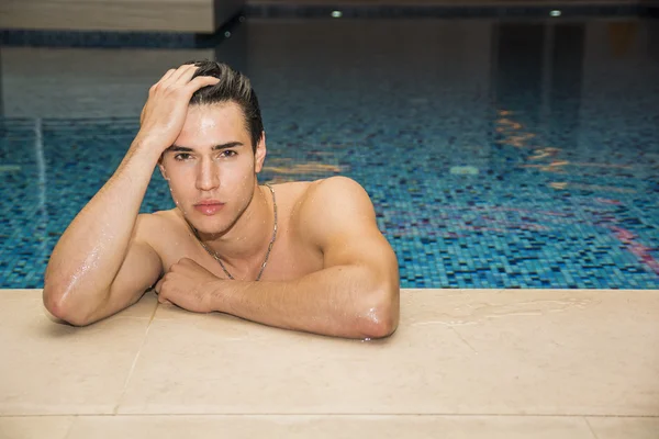 Homem jovem relaxante na piscina — Fotografia de Stock
