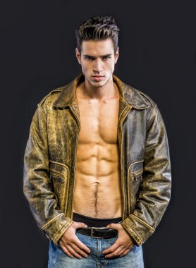 Çıplak gövdeye deri ceket giyen yakışıklı genç adam.