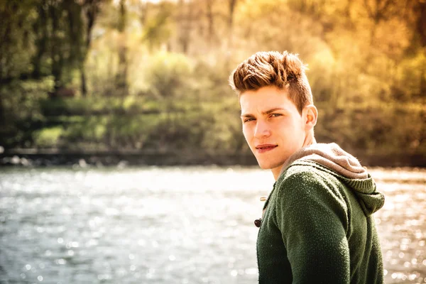 Kontemplativní dospívající chlapec seděl vedle řeky — Stock fotografie