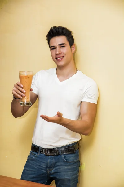 Young man drinking big glass of healthy fruit smoothie — kuvapankkivalokuva