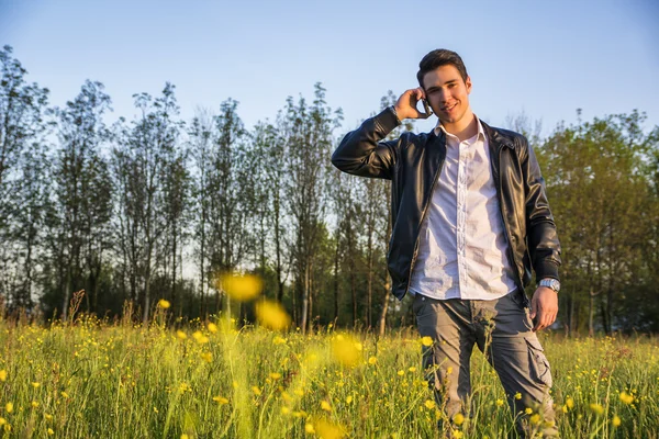 Pohledný mladý muž na venkově, pomocí mobilního telefonu — Stock fotografie