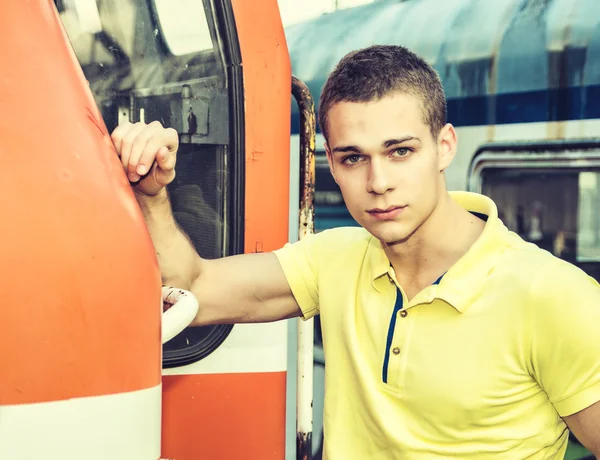 Handsome young man in polo shirt in front of train —  Fotos de Stock