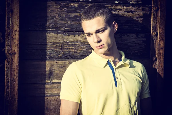 Handsome young man next to wood planks wall — Stockfoto