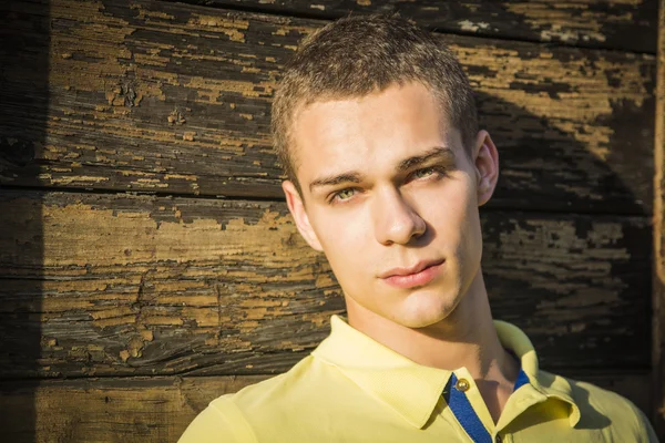 Handsome young man next to wood planks wall — Stock fotografie