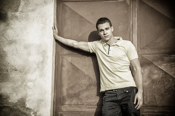 Young man leaning against wall outside — Stock Photo, Image