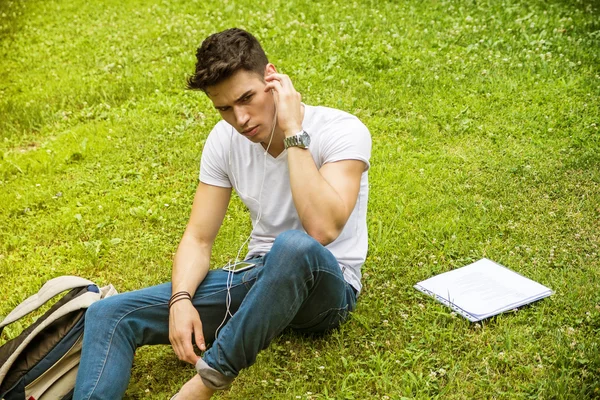 Unge mann som hører på musikk i Park – stockfoto