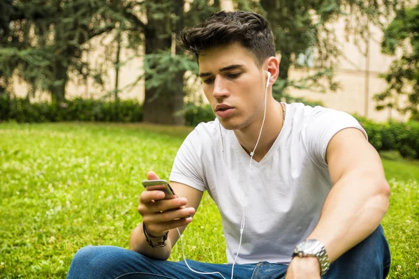 Молодой человек слушает музыку в парке — стоковое фото