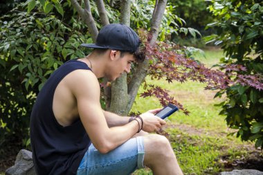 Young Man with Tablet or Ebook Reader Relaxing at Park