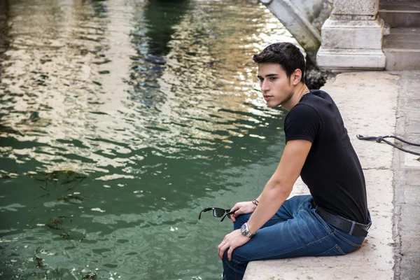 Jeune homme assis à côté de Canal à Venise, Italie — Photo