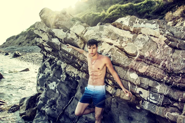 Молодой спортсмен без рубашки стоит в воде у берега океана — стоковое фото