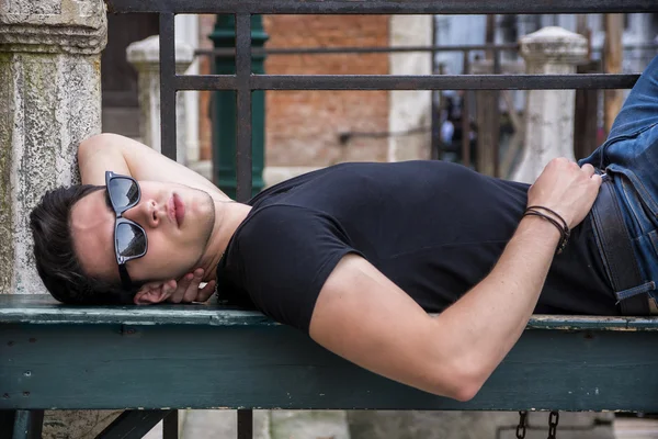 Séduisante jeune homme portant sur le banc en bois — Photo