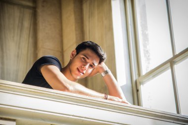 Young Man Smiling, Resting with Head on Staircase Railing