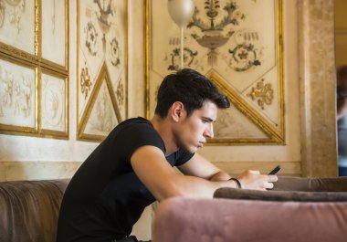 Young man in elegant place using cell phone