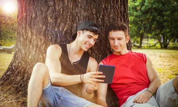 Two friends watching something on tablet or ebook reader — Stok fotoğraf