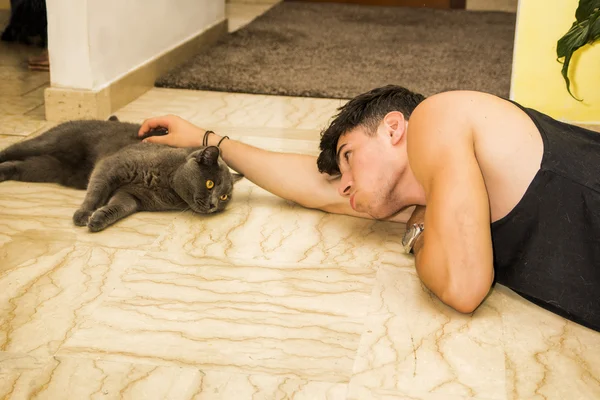 Young Man Lying on Floor Petting Pet Cat — Stok fotoğraf