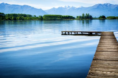 Wooden small pier over peaceful lake clipart