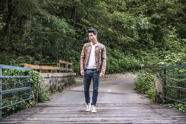 Handsome athletic young man hiking on bridge in forest — Stock Photo, Image