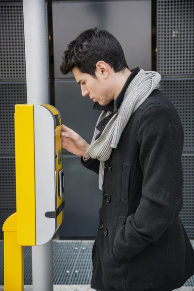 Handsome stylish young man bending down to talk on speaker phone — Fotografia de Stock