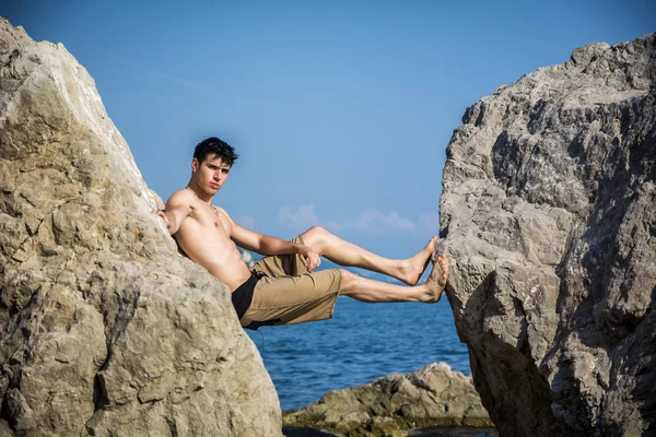 Mladý muž Spanning propast mezi pobřežní balvany — Stock fotografie