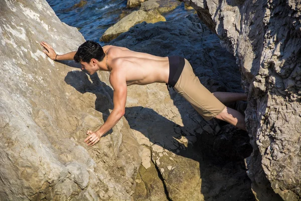 Junger Mann spannender Kluft zwischen Küsten Felsbrocken — Stockfoto