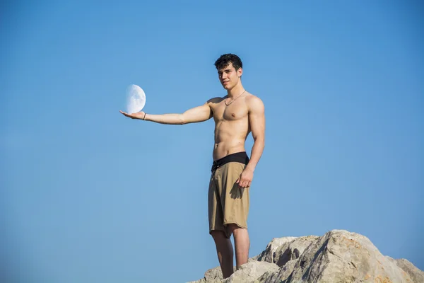 Muskulöser junger Mann mit nacktem Oberkörper gegen den Himmel mit Mond — Stockfoto