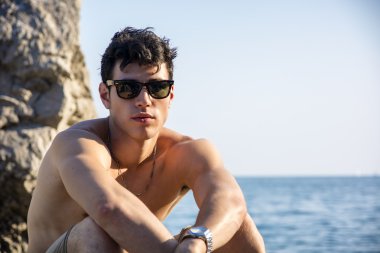 Handsome young man on beach with wet hair and sunglasses