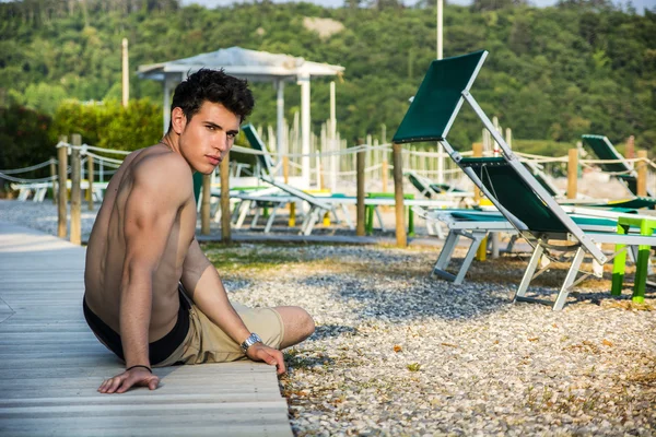 Mladý muž leží na břiše na sluneční palubě — Stock fotografie